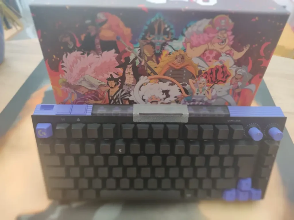 Tastatura Logitech G512 X 75 sprijinita de o cutie cu design One Piece, cu tastele Caps Lock si rotitele vizibile