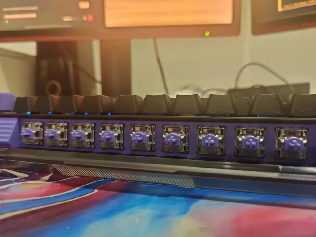 Switch uri analogice Logitech G512 X 75 la vedere, cu iluminare RGB albastra si simbol distinctiv mov