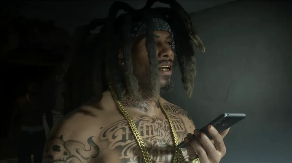 Raymond, un membru tatuat al găștii San4san, se uită pe telefon într-o cameră slab luminată, captură din GTA 6
