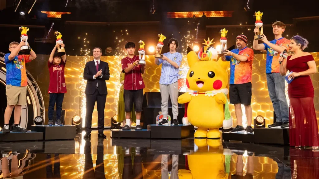Campioni ținând trofee pe scenă alături de o mascotă Pikachu, la ceremonia de închidere a Campionatelor Mondiale Pokemon 2026 din San Francisco